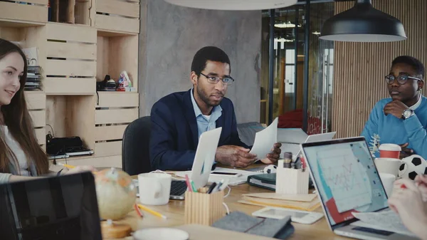 Feliz jefe de la compañía afroamericana se ríe de la reunión multiétnica de la oficina, luego se vuelve serio de nuevo en el coworking de moda 4K — Foto de Stock