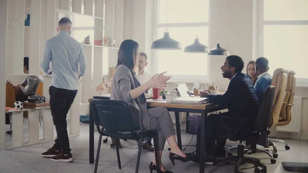 Dolly toma de trabajo en equipo en la mesa de oficina moderna loft. Los empresarios multiétnicos cooperan, discuten el mercado en la reunión 4K . — Foto de Stock