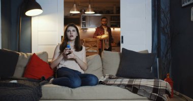 Mutlu, genç, Kafkasyalı romantik çift, evde sakin bir film gecesi için birlikte oturur, atıştırmalıklar ve ağır çekimde içer..