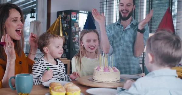 Felice giovane ragazza caucasica adolescente bambino che festeggia il compleanno con la famiglia, soffiando su candele torta a casa rallentatore . — Foto Stock