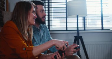 Yan görünüm genç Avrupalı arkadaşlar oyun konsolu ile oyun oynuyorlar evde yavaş çekimde eğleniyorlar.