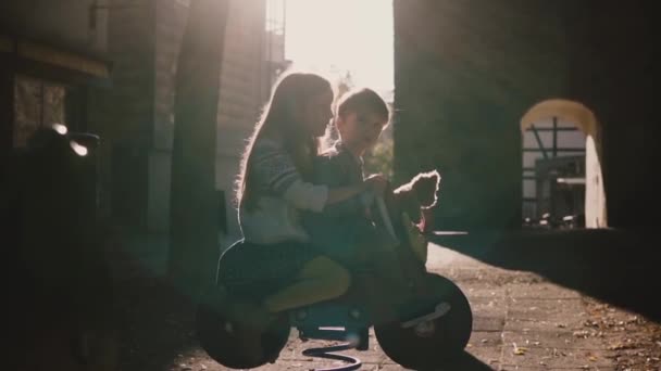 Ragazzino e ragazza insieme a cavallo cavaliere primaverile. Carino bambini europei divertirsi al parco giochi estivo al mattino . — Video Stock