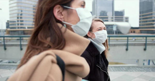 Assistentes sociais de controle epidêmico. Duas jovens médicas caucasianas mascaradas caminham na rua da cidade durante a quarentena . — Fotografia de Stock