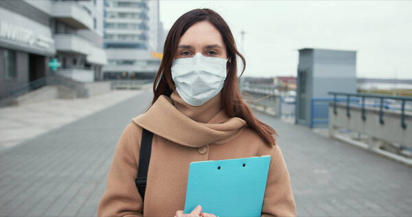 Epidemic control worker. Portrait of Caucasian social care woman in medical face mask in empty street during quarantine.
