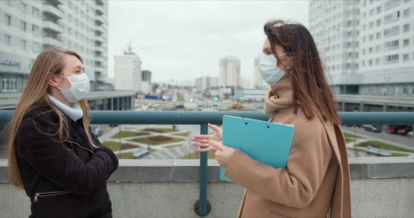 Controllo epidemico assistenti sociali. Due giovani donne caucasiche dipendenti di assistenza sociale in maschere viso parlare al di fuori . — Foto Stock