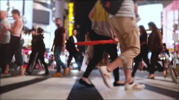 Atmosférica toma en cámara lenta de las piernas de la gente caminando por la calle llena de pantallas publicitarias por la noche en la ciudad de Nueva York . — Vídeo de stock