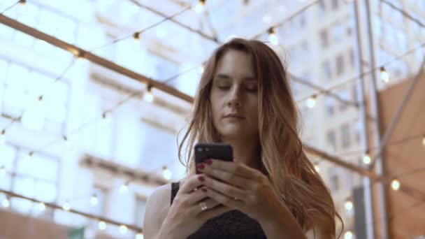 Портрет молодої вродливої жінки, що стоїть у торговому центрі і користується смартфоном, переглядає Інтернет.. — стокове відео