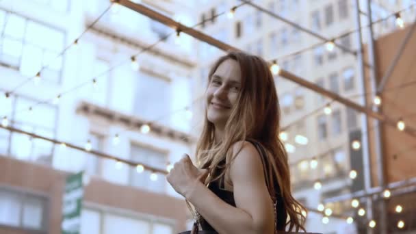 Portrait de jeune belle femme heureuse debout dans le centre commercial et montrant les sacs des magasins avec des achats . — Video