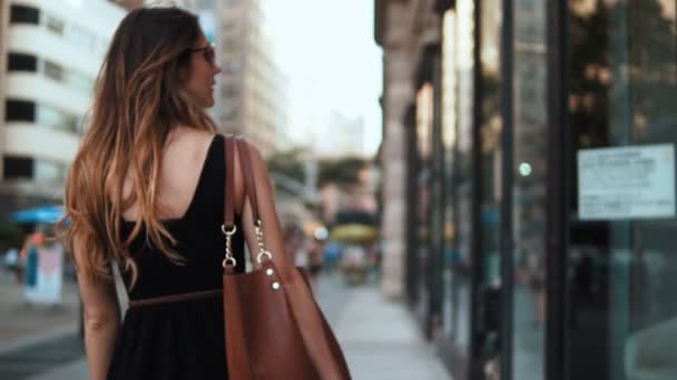 Vista posteriore di giovane bella donna con borse della spesa passeggiando per la strada in centro. Rallentatore . — Video Stock