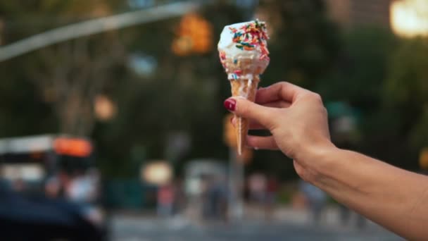 Detailní pohled na ženskou ruku držící tající zmrzlinu s barevným vrcholem u silnice. Zpomalený pohyb. — Stock video
