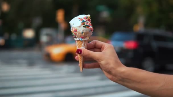 Vista de cerca de la mano femenina sosteniendo el helado derretido con cobertura cerca de la carretera en el caluroso día de verano. Movimiento lento . — Vídeos de Stock