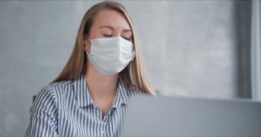 Genç Kafkas doktor kadın internette dizüstü bilgisayar kullanıyor, karantinadaki insanlara yüz maskesi takarak danışmanlık yapıyor..
