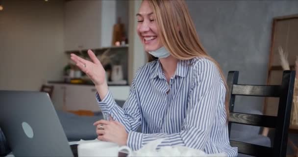 아름답고 행복 한 금발의 젊은 여성 이 컴퓨터를 사용하여 친구들 과 화상 통화를 할 때 얼굴에 마스크를 벗고 이야기를 나눈다. — 비디오