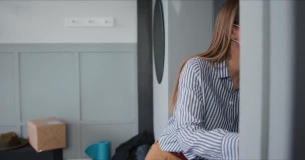 Conceito de auto-isolamento, jovem mulher caucasiana usando máscara de segurança recebe sacos de entrega de alimentos do correio durante o bloqueio . — Vídeo de Stock