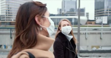 Salgın hastalık koruması. İki mutlu Kafkas iş kadını karantina sırasında şehir caddesinde yürürken yüz maskesi takıyor..