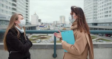 Salgın kontrol sosyal hizmetler görevlileri. Yüz maskeli iki beyaz kadın sosyal hizmetler görevlisi dışarıda konuşuyor..