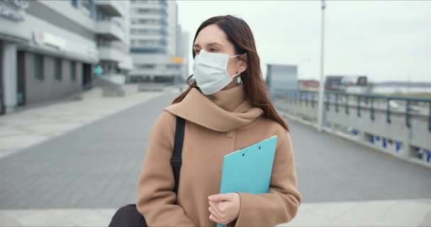 Epidemie COVID-19, portrét pracovníka sociální péče. Mladá běloška nosí lékařskou masku obličeje venku během karantény. — Stock video