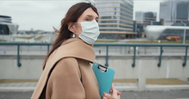 Карантин эпидемии коронавируса. Портрет социального работника, юная брюнетка в защитной маске снаружи — стоковое видео