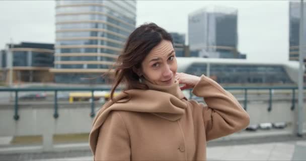 Portrét krásné šťastný zdravý elegantní obchodní žena v béžovém kabátě při pohledu na kameru usmívající se v pozadí města. — Stock video