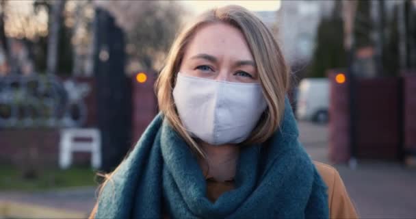 Situation pandémique. Portrait de jeune femme blonde portant un masque de protection du visage à l'extérieur pendant le confinement du virus COVID-19 . — Video