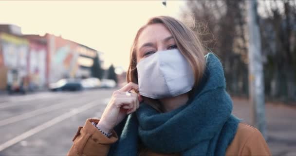 Quarantine ending. Portrait of young happy Caucasian woman taking safety mask off smiling outdoors, the lockdown is over — Stock Video