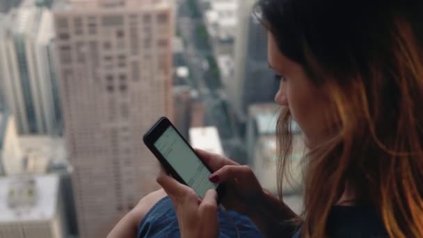 Молода жінка користується смартфоном у хмарочосі. Жінка друкує повідомлення по телефону і насолоджується панорамою Чикаго (Америка).. — стокове відео