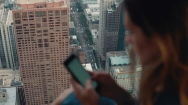 Akıllı telefon kullanan genç ve çekici bir kadın. Chicago, Amerika 'da, gökdelende pencerenin yanında duran kadın..