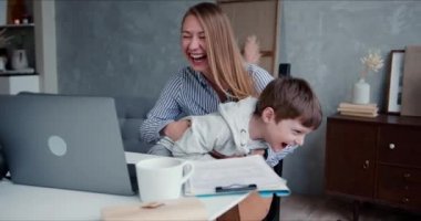 Karantinada aile eğlencesi. Genç, mutlu, beyaz bir anne ve sevimli bir oğul dizüstü bilgisayardan çizgi film izlerken gülüyorlar..