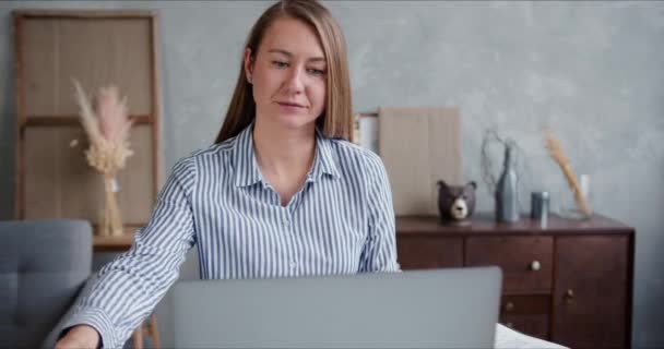 A trabalhar no auto-isolamento. Jovem feliz positiva mulher de negócios caucasiana trabalha a partir de casa usando laptop vídeo conferência . — Vídeo de Stock