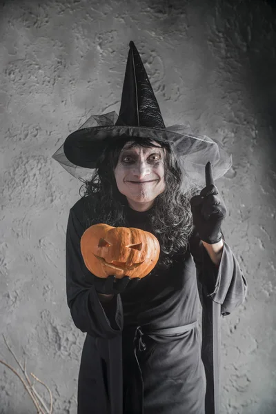 Bruja de Halloween sosteniendo una calabaza — Foto de Stock