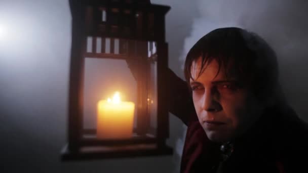 Un vampiro con una lámpara en las manos en la niebla de la noche (hombre aterrador vestido con disfraz de Halloween ) — Vídeo de stock