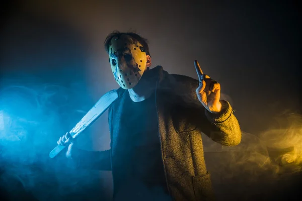 Un tueur en série homme caucasien avec portrait masque en studio de silhouette, masque blanc de hockey effrayant sur jeune homme brandissant une machette — Photo