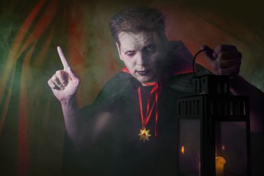 koyu arka plan üzerinde siyah Fener giyiyor ile parmak cape işaret spooky halloween vampire