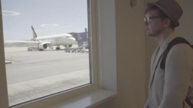 Havaalanında uçak önce hareket izlerken pencerenin yanında duran adam turist genç adam