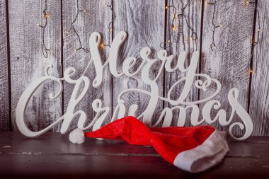 Beyaz neşeli Noel işareti ve Noel şapka ile ışık ahşap arka plan üzerinde