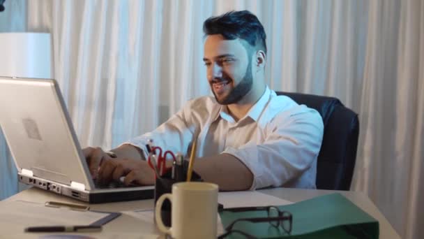 Joven empresario sentado en la oficina y trabajando con el ordenador portátil — Vídeo de stock