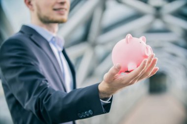 pembe bulanık kumbara el üzerinde arka planda tutan giyen takım elbise genç adam