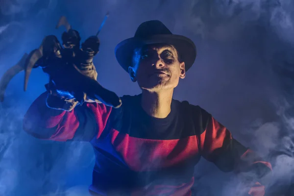 Mannen är en seriemördare med en handske c vassa knivar i dimman, bakgrunden för Halloween — Stockfoto