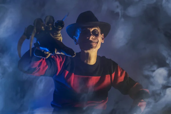 El hombre es un asesino en serie con un guante c cuchillos afilados en la niebla, fondo para Halloween — Foto de Stock