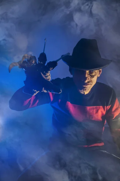 Mannen är en seriemördare med en handske c vassa knivar i dimman, bakgrunden för Halloween — Stockfoto