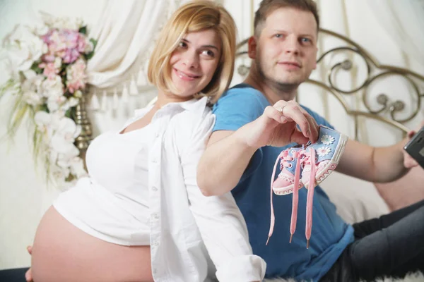 Beautiful Young Couple Holding Children Boots Smiling Sitting Bed — Stock Photo, Image