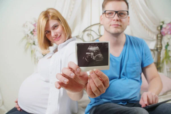 Belo Jovem Casal Segurando Sonograma Bebê Sorrindo Sentado Cama — Fotografia de Stock