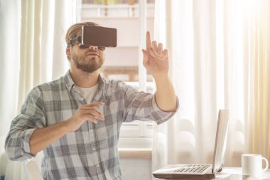 Modern iç mekanlarda sanal gerçeklik gözlüğü takan genç sakallı adam. Yakışıklı beyaz erkek VR kulaklık kullanıyor, video oyunları oynuyor..