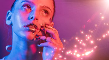 Model metalik gümüş dudaklar ve neon mavisi ve mor renkli yüzlü kadın, stüdyoda poz veriyor, güzel kız, parıldayan makyaj, renkli.
