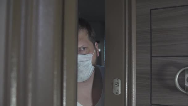 Covid 19コロナウイルス隔離コンセプト 医療マスクの男が家のドアを開ける 呼吸器保護 — ストック動画
