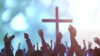 Bir Hıristiyan toplantısındaki kalabalığın elleri çarmıhın arka planına karşı Allah 'ı överek övüyor.