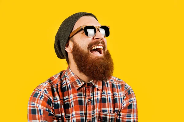 Ritratto di giovane hipster in occhiali da sole e cappello in posa su backogrund giallo — Foto Stock