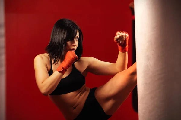 Attractive young woman working out a gym. Close up image of middle eastern female in sports clothing. Fit body of beautiful, healthy and sporty girl. Boxing training woman with punching bag in gym.