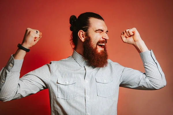 Felice uomo hipster barbuto sorridente in casual celebrare la vittoria con le mani in alto. Concetto vincitore . — Foto Stock