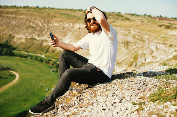 Улыбающийся молодой бородатый хипстер веселится на улице
